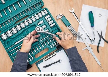 Man working in workshop using many tools. Wrench, spanner, calliper and ratchet with many attachments. Work tools. Universal tool set. Professional equipment