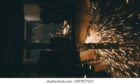 Man works circular saw. Industrial professional worker grinding metal. Craftsman sawing metal with disk grinder in workshop. Sparks fly from hot metal - Powered by Shutterstock