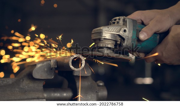 man works with a circular saw. Sparks fly from the\
hot metal. man was working hard on steel. Close-up, slow motion in\
garage. An angle grinder cuts an iron billet clamped in a\
locksmith\'s vise.