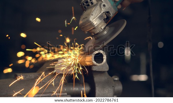 man works with a circular saw. Sparks fly from the\
hot metal. man was working hard on steel. Close-up, slow motion in\
garage. An angle grinder cuts an iron billet clamped in a\
locksmith\'s vise.