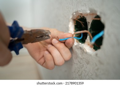 man works with electrical wires using tools, fixing socket at home, male household work with electricity, pliers and wire cutters in man's hands, electrician working with wire - Shutterstock ID 2178901359
