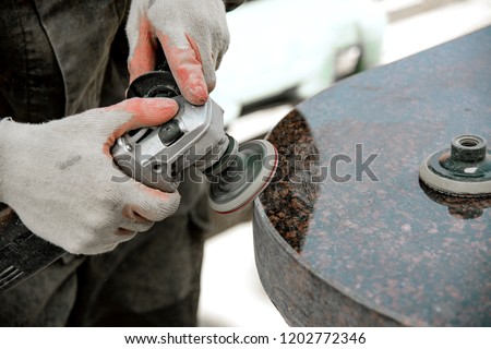 A man works polishing a marble stone with an angle grinder. iznotovlenie monuments of natural stone