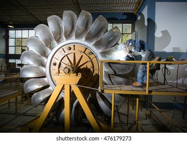 A man works welding on Pelton wheel.