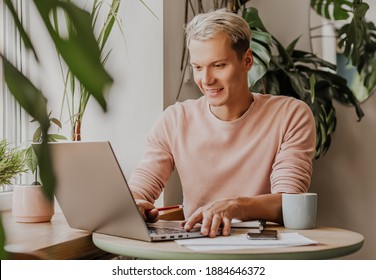 Man works in the workplace with documents and and drinks coffee in an eco cafe with plants
