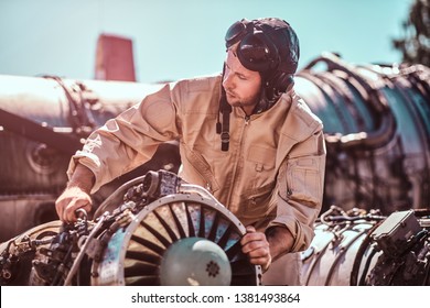 Man at workshop's outside is fixing his own jet. He is holding a part of turbine. Man is wearing pilot's helmet. - Powered by Shutterstock