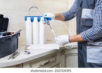  man in workwear installing water filtration system in a kitchen. - Powered by Shutterstock