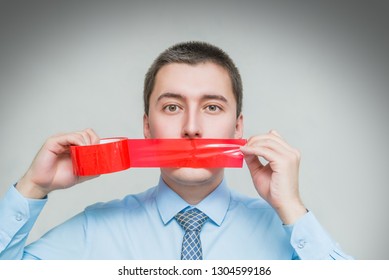 Man With Wrapping Adhesive Tape Around Mouth. Businessman Silenced With Duct Tape Over His Mouth. Frightened Man Covered Mouth With Red Insulating Tape