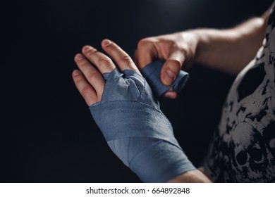 Man is wrapping hands with blue boxing wraps. Isolated on black with red nails. Strong hand and fist, ready for fight and active exercise. Matte wash image. - Powered by Shutterstock