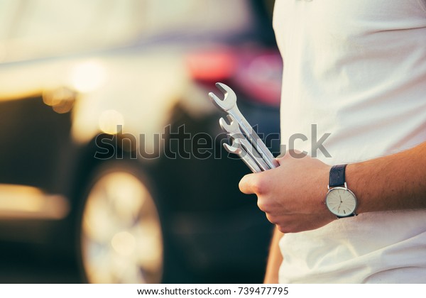 Man with wrench\
in hands repair car on road