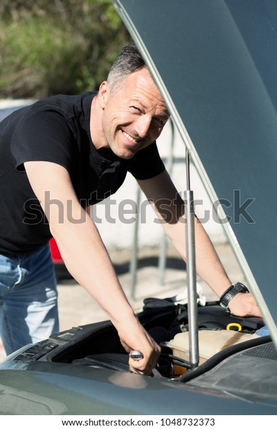 Man with\
wrench and other tools standing near car.  Man repairing the engine\
in the car. Auto repair. Auto\
Mechanic.