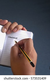 Man write Checklist on note book with dark blue background