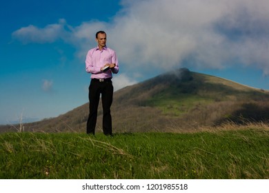 man writes in notepad sitting on mountain