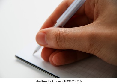 man writes with a pen in a notebook