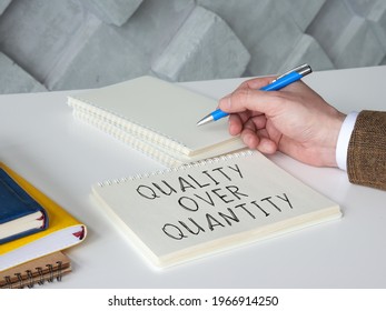 Man Writes Phrase Quality Over Quantity On The Page.