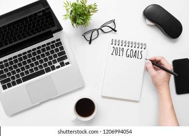 Man is writing 2019 goals on notebook, new year resolutions concept. Top view, flat lay image.