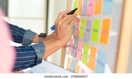 Man Is Writing By The Right Hand On Notepapers That Stick On White Board. Wears Stripped Blue Shirt. Hands And Notepapers.