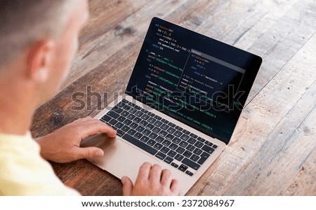 Man writing computer code on laptop