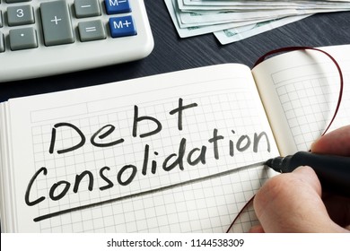 Man is writing debt consolidation in the note. - Shutterstock ID 1144538309