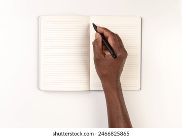 Man writing or drawing with a black pen in a notebook, diary or a calendar, on a white desk, top view - Powered by Shutterstock