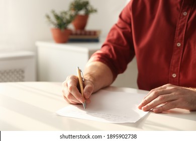 Man Writing Letter At White Table In Room, Closeup