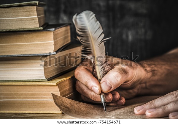 Man writing an old\
letter. Old quill pen, books and papyrus scroll on the table.\
Historical atmosphere.