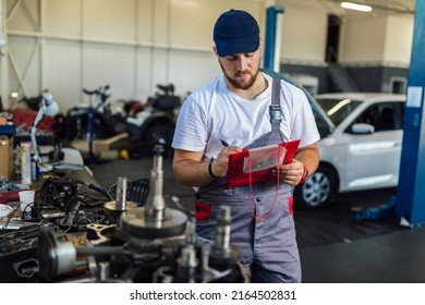 Man writing on a clipboard in a garage. - Shutterstock ID 2164502831