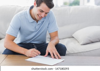 Man Writing On A Paper While He Is Sat On A Couch