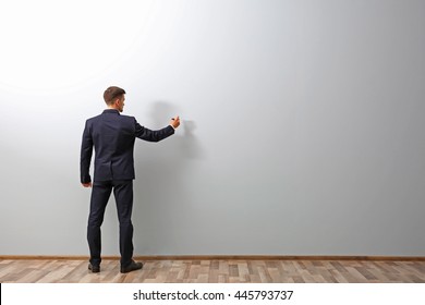 Man Writing Something On Grey Wall