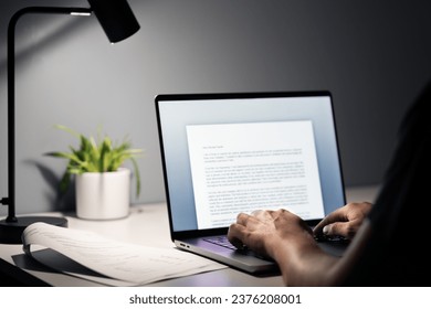 Man writing text document, essay or letter with laptop. Freelance writer, journalist or entrepreneur working late at night, overtime. Job seeker, cv resume and application. Dark home or office room.