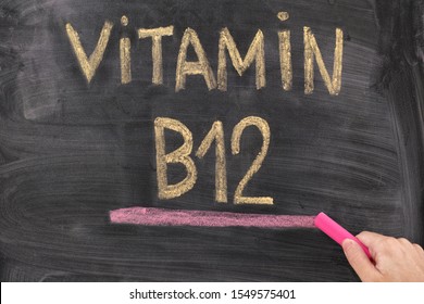 Man writing words Vitamin B12 on chalkboard. Vitamin B12 Concept. Close up.