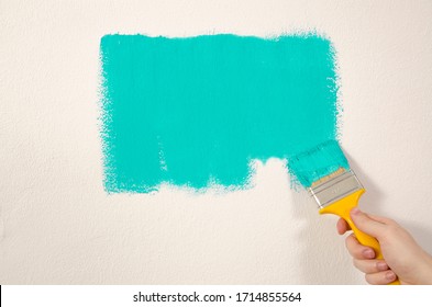 Man with Yellow brush painting the wall with green color 