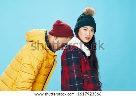 a man in a yellow jacket and hat leaned on the back of a woman