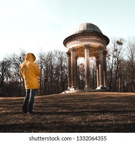Man in yellow jacket standing in front of a old building in a forest