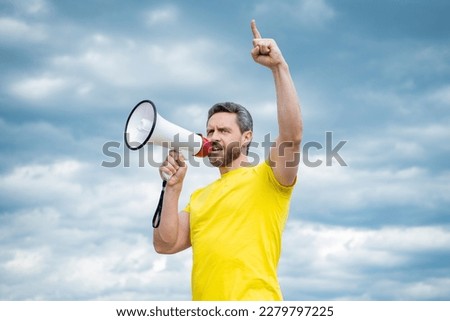 man in yellow shirt agitate in loudspeaker on sky background