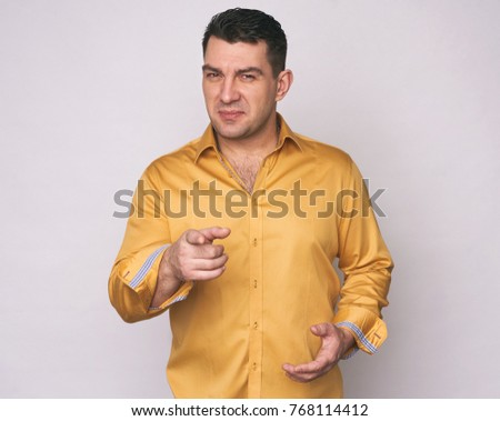 man in yellow shirt pointing at you. Isolated on gray