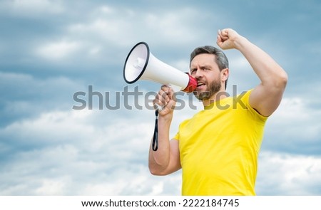 man in yellow shirt proclaim in loudspeaker on sky background