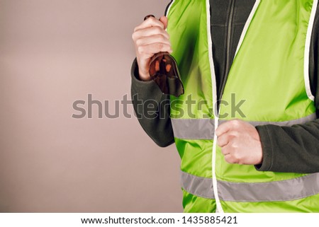 man in a yellow vest protesting with a broken bottle in his hands