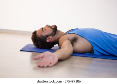 Man In Yoga Corpse Pose In Fitness Studio