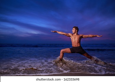 Man In Yoga Warrior Pose On Ocean Beach At Dusk