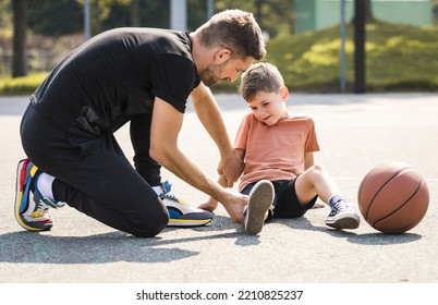 A man and young boy playing basketball on a court, the boy having ankle injury and crying