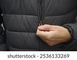 A man zipping up his puffer jacket. Close up.