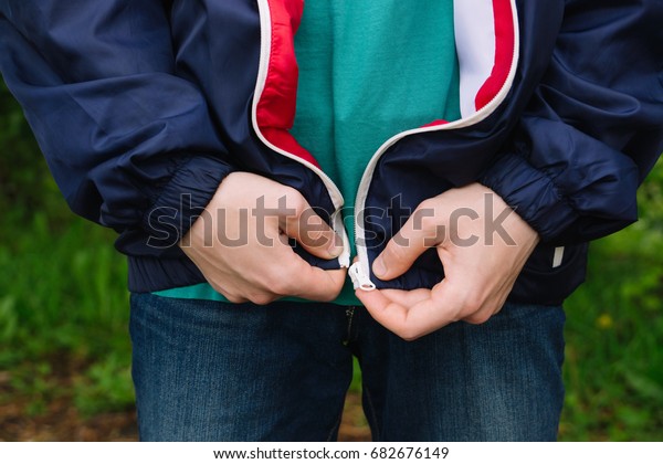 A man zips up a jacket. Hands closeup. Natural.\
It\'s cold outside.