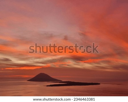 Manado City, North Sulawesi Province, Indonesia - 30 July 2033: The view of Mount Manado Tua and Bunaken Island at sunset has a beautiful orange color. Picture taken from Mount Tumpa, Manado City
