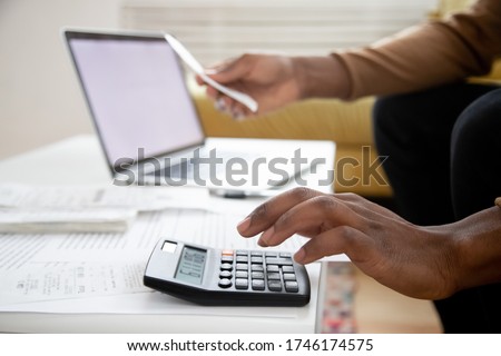 Manage planning family budget, savings and payment concept. Close up image hands of African man using calculator calculates finances checking family expenses, do small business, month result analysis