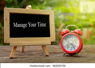 MANAGE YOUR TIME! inscription written on chalkboard and red alarm clock on  old wooden desk . Time concept. - Shutterstock ID 582055750
