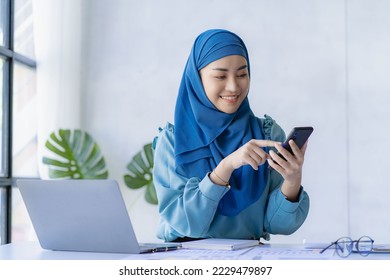 Management concept drives organizational growth of female leaders. Asian Muslim woman wearing hijab sits in the office of a start-up company. which is managed and run by young women - Powered by Shutterstock