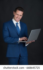 Manager, Businessman Or Happy Man Smiling With Laptop On Black Background. Formal Blue Suit And Tie. Technology For Business. Fashion And Dress Code