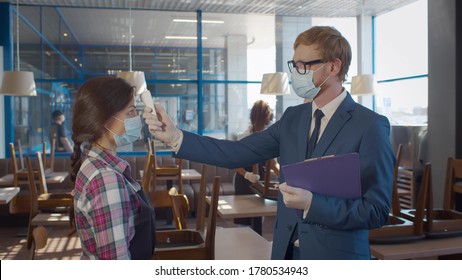 Manager checking body temperature of staff using thermal scanner in coffee shop. Cafe owner in mask and gloves measuring temperature of waitress before start working. Restriction and covid-19 - Powered by Shutterstock