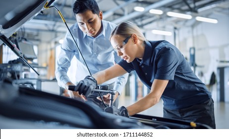 Manager Checks Diagnostics Results on a Tablet Computer and Explains an Engine Breakdown to an Female Mechanic. Car Service Employee Uses a Ratchet to Fix the Engine Component. Modern Clean Workshop. - Powered by Shutterstock