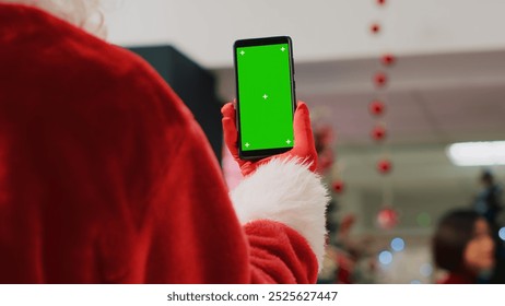 Manager in Christmas adorn shopping mall wearing Santa Claus suit holding mockup smartphone, reading promotional holiday offers for customers on green screen, close up shot - Powered by Shutterstock